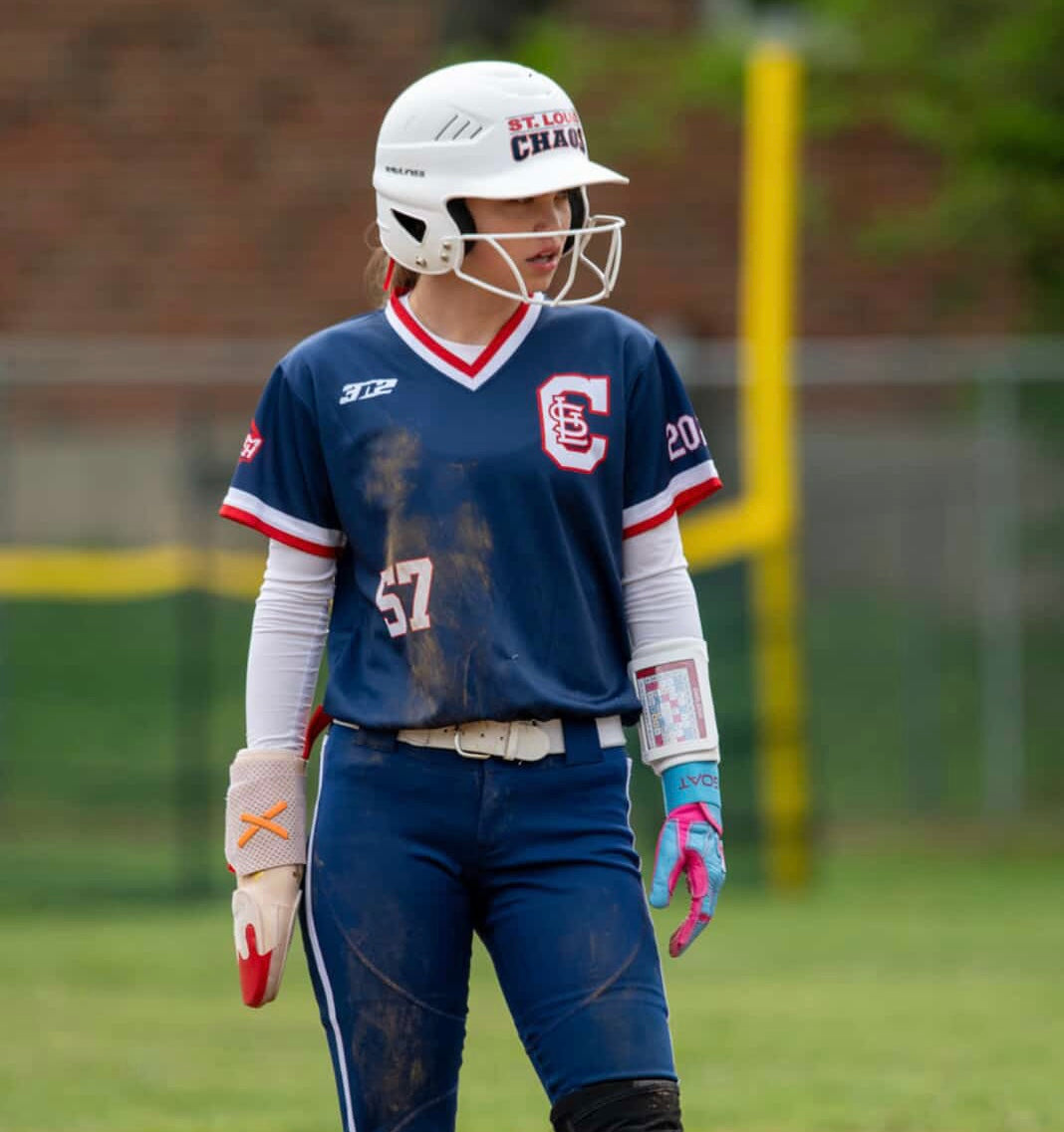 Player wearing GOAThletic blue and pink batting glove and arm compression sleeve on field