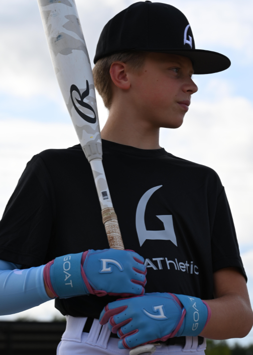 Youth baseball player wearing GOAThletic blue arm compression sleeve and batting gloves holding bat